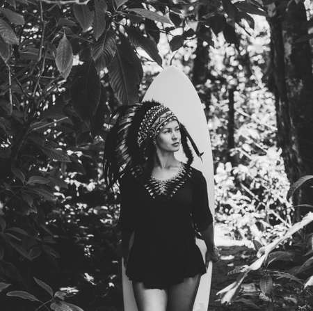 Semi-naked and calm woman posing in the woods wearing conceptual mayan indian chief headdress made...
