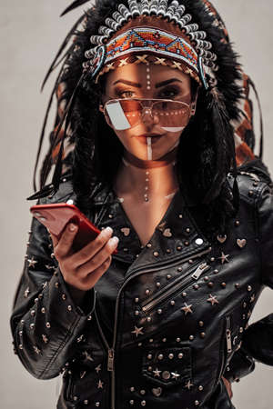 Beautiful and confident female wearing American indian traditional headdress, leather jacket and...