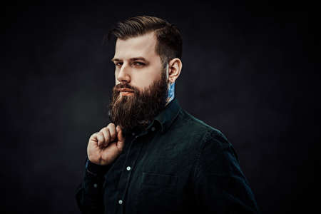 Young stylish hipster guy posing in dark studio
