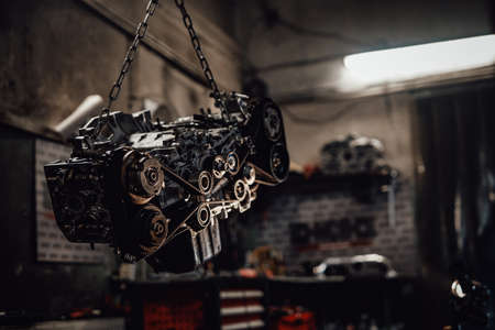 Closeup view of a suspended boxer engine in a dark garage or workshopの写真素材