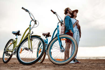 Young couple, looking at the sea with two bikes in front of themの写真素材