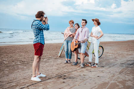 A group of friends, taking photos on the beach with a guitarの写真素材