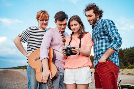 Friends are checking new photos that they have taken on the beachの写真素材