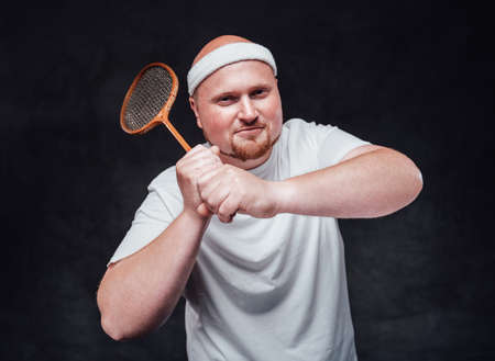 A man in white sportswear holds a racket with two hands