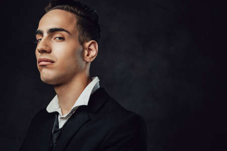 Close up portrait of a stylish and elegantly dressed young man on a dark background