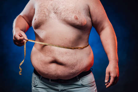 Overweight man with tape is measuring fat on belly