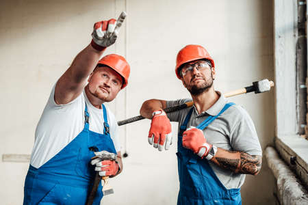 Chunky and thin workers, discussing the upcoming work at the construction siteの写真素材