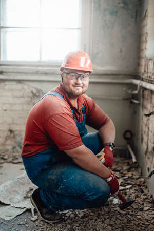 Highly skilled and smiling worker handling a brick wall on a big construction site