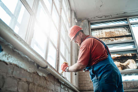 Concentrated and highly skilled worker handling a windowsill on a large construction siteの写真素材