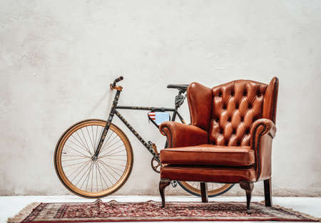 Custom made bicycle, old carpet and luxury retro armchair in a white roomの写真素材