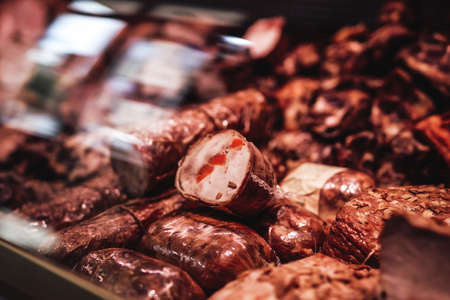 A lot of smoked meat in a butcher shop. Deli salted and fresh meat selling. Brown smoked meat counter.の写真素材