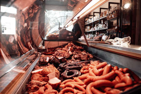 Huge assortment of sausages in a shop window. Different fresh and deli sausages in a single store. Meat business.の写真素材