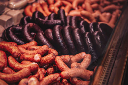 Cold and fresh smoked meat in the market. Butcher shops meat counter. Saling sausages and hum.の写真素材