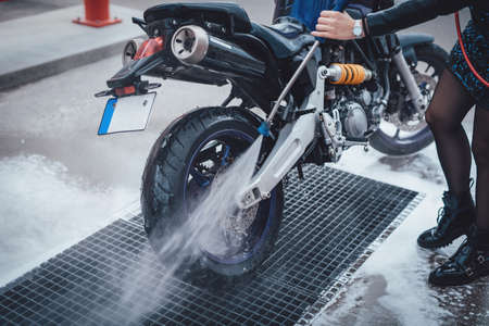 Sport motorcycle are taking care by the girl. Female cares about her bike. Shiny and illuminated photo in car wash service.の写真素材