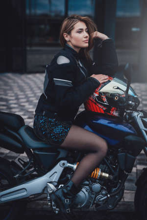 A nice looking woman at the streets with her urban sport motorcycle. Motorbike sport hobby. Modern custom bike.の写真素材