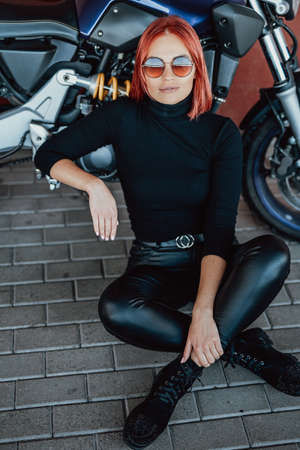 Modern youth motosport hobby. A cute girl posing with her custom sport motorcycle on the bridge. Light photo of moto passion.の写真素材