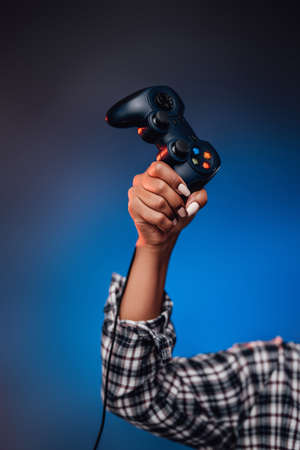 Groomed and pretty afro womans hand is holding a joystick and pointing it up in foggy blue...