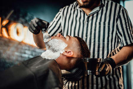 Retro styled barbershop working and serves a man which came for haircutting to favourite caucasian barber.の写真素材