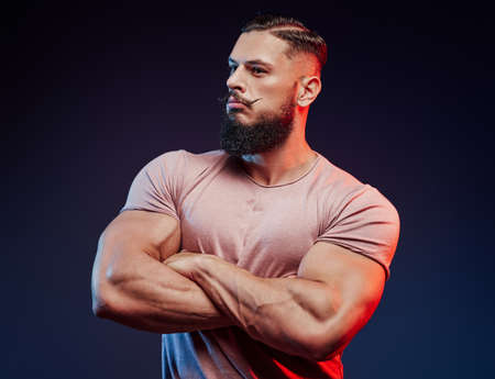 Bodybuilder in shirt with black beard and with fashionable hairstyle posing with crossed arms.の写真素材