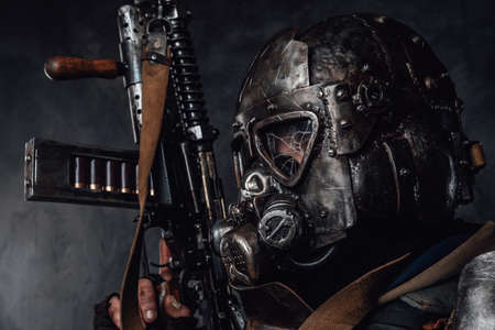 Headshot of ragged stalker in helmet with broken glass and custom armour with riffle in dark background.の写真素材