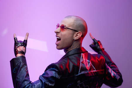 Stylish and joyful rocker in black leather jacket and gloves with short haircut and glasses...