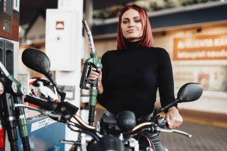 Sunny vintage photo of girl which rides her urban bike in service. Custom motorcycle and its female onwer. Female biker.の写真素材
