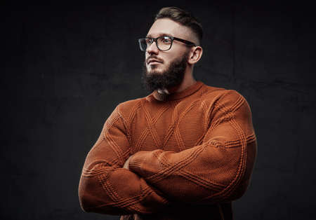 Posing in dark background with crossed arms strong guy in sweater with glasses and beard.の写真素材