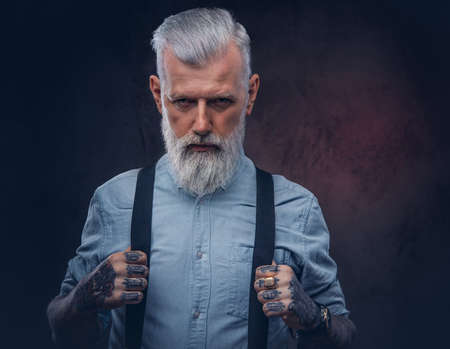 Portrait of elegant and stylish grandfather with modern hairstyle in shirt which poses in dark background.の写真素材