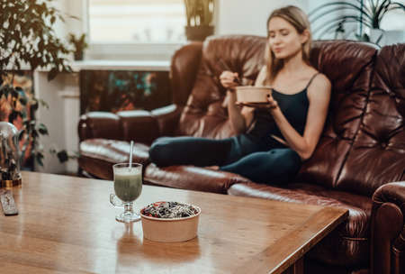 Healthy eating. A table and salad with cocktail on it in background of blurred woman which sits on...