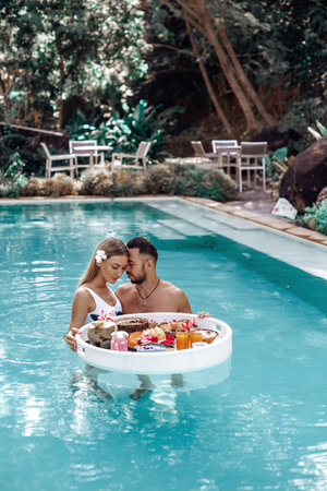 Luxurious hotel for relaxation and recreation in Thailand. Beautiful woman with her loving husband swims in a pool.の写真素材