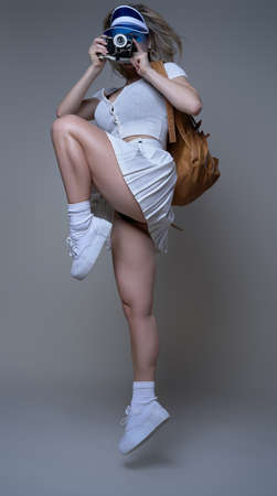 Sportswoman with photocamera shots and poses in white background. Portrait of a female athlete...