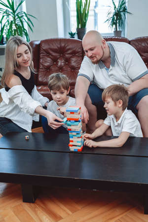 Concept of family they spend time together and have fun. Joyful brothers and their parents play  game in living room.の写真素材