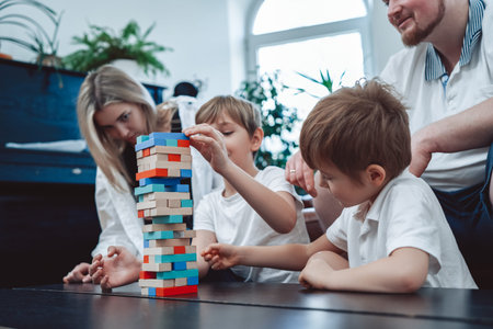 Two youth boys construct a tower from bricks competing each other and with their parents at home.の写真素材
