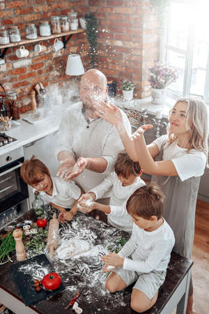 Domestic lifestyle and food cooking. Atmospheric portrait of young father and mother with their three youth sons they prepare food.の写真素材