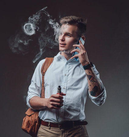 Elegant hipster man dressed in formal custom clothing isolated in dark background. Stylish tourist...