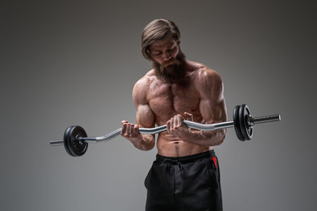 Caucasian handsome athlete looking at barbell he holds itの写真素材