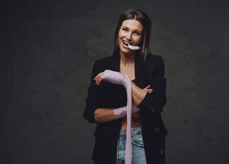 Joyful female sportsperson dressed in black jacket poses in dark backgroundの写真素材