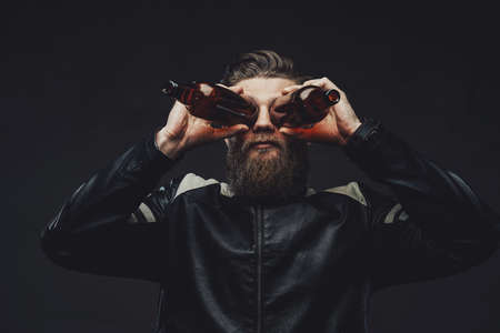 Guy with beard in jacket holding bottles like binocularsの写真素材