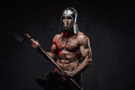 Viking with naked torso and beard posing in dark background