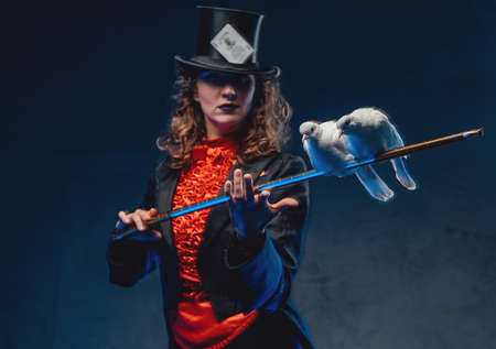 Mystical woman holding a stick with two pigeons in dark backgroundの写真素材