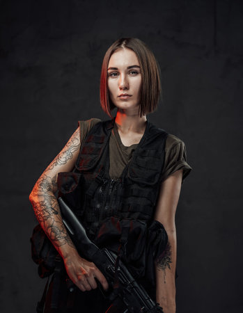 Tattoed martial woman in black armour with assault rifle