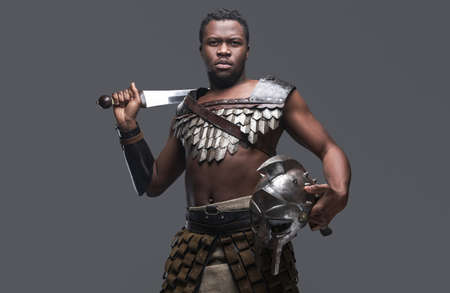 Violent gladiator with sword against gray backgroundの写真素材