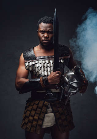 Studio shot of fearful authentic gladiator of african descent with gladiusの写真素材
