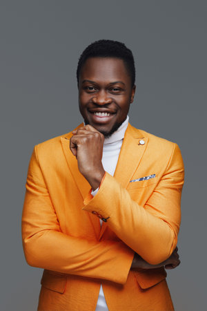 Happy fashion guy in orange coat against gray backgroundの写真素材