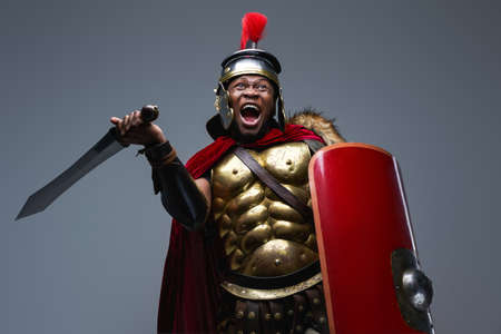 Screaming roman warrior assaults against gray backgroundの写真素材