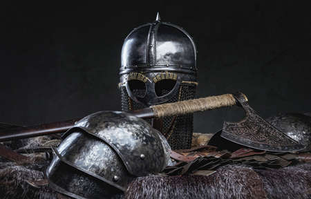 Isolated in dark background antique knight armor with helmet on fur with axe.の写真素材