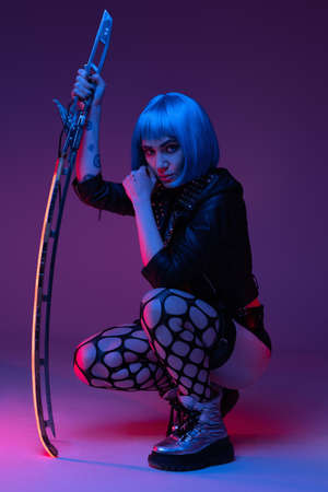 Martial cyberpunk hipster woman with sword inside studioの写真素材