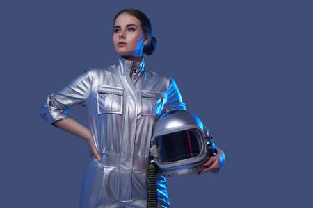 Modern female cosmonaut posing against blue backgroundの写真素材