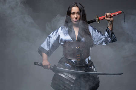 Oriental woman samurai with katanas in fog