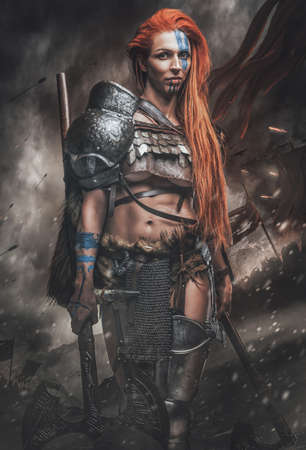 Nordic woman warrior with axes in battlefieldの写真素材